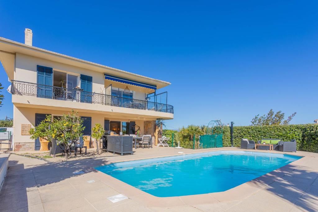 a villa with a swimming pool in front of a house at Appartement Le Figuier in Fréjus