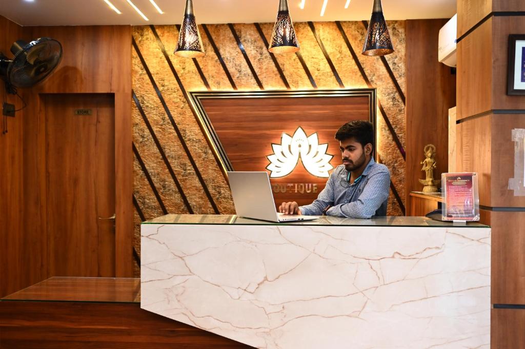 un homme assis à un comptoir avec un ordinateur portable dans l'établissement Mohar Residency, à kolkata