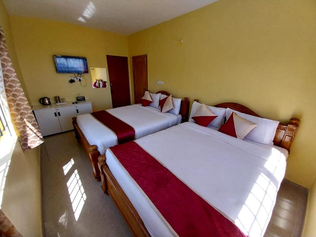 a bedroom with two beds with red and white sheets at JRS INN, KODAIKANAL in Kodaikānāl