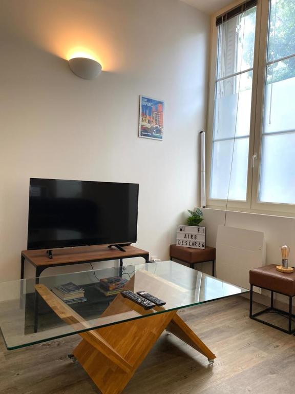 a living room with a glass table and a tv at Le Descartes: cosy in the city centre in Poitiers