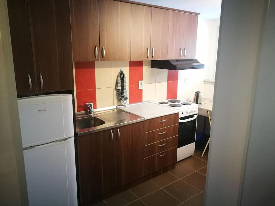 a kitchen with wooden cabinets and a white refrigerator at Cozy apartment for short term rent. in Káty