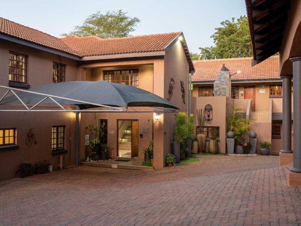 un patio de una casa con una sombrilla grande en Casa Albergo Corporate Guest House en Pretoria