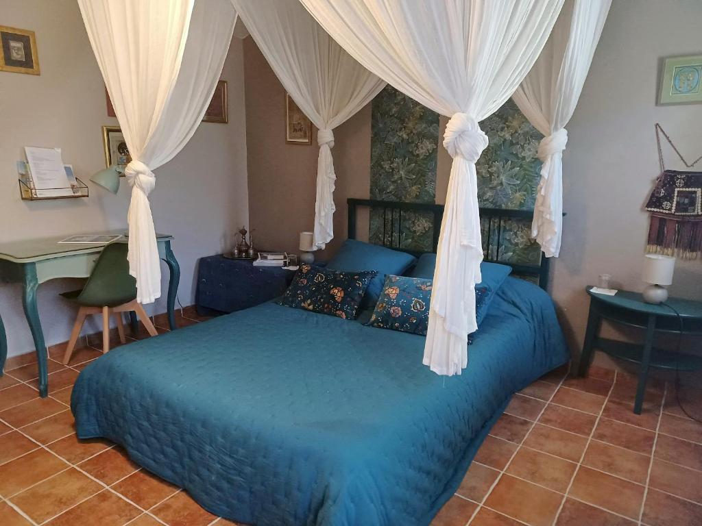 ein Schlafzimmer mit einem blauen Bett mit Vorhängen und einem Schreibtisch in der Unterkunft Une chambre en Provence in Correns