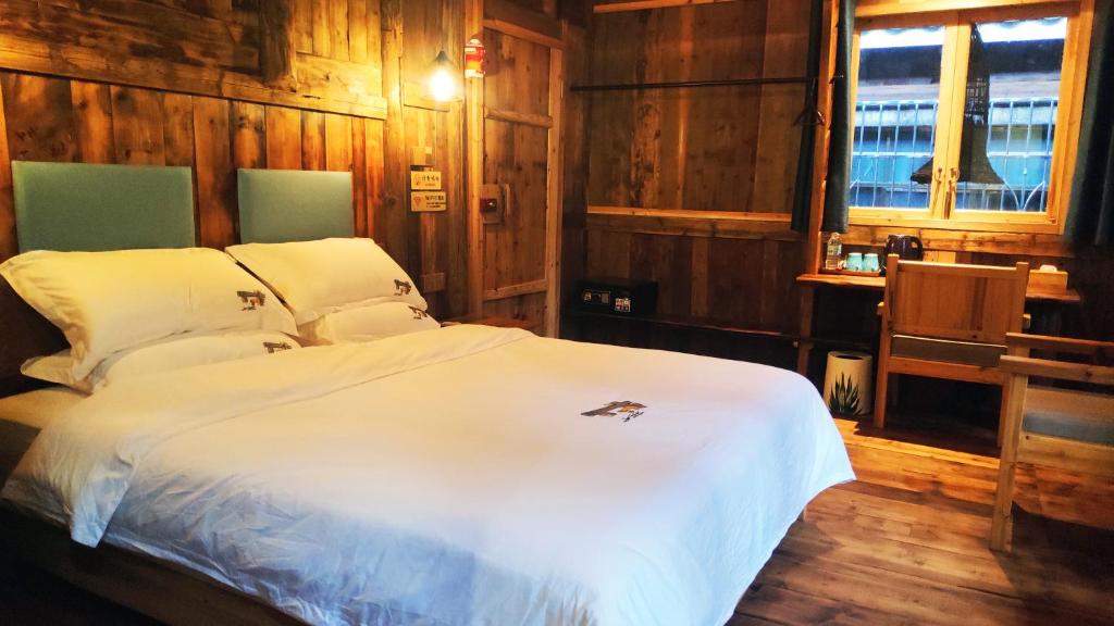 Schlafzimmer mit einem weißen Bett und Holzwänden in der Unterkunft Lost World Sanjiang Guest house in Sanjiang