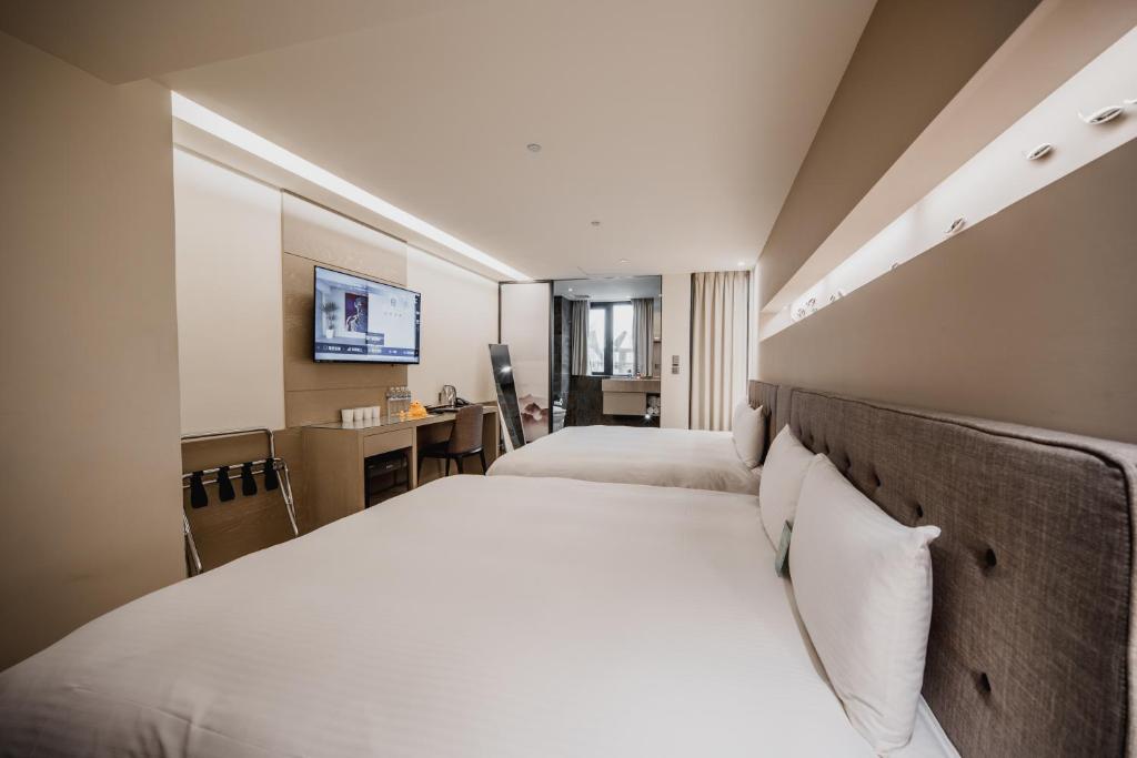 a hotel room with two beds and a desk at Hub Hotel Kaohsiung Yawan Branch in Kaohsiung