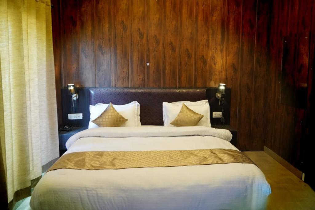 a bedroom with a large bed with white sheets and pillows at Vacay inn Hotel in Nainital