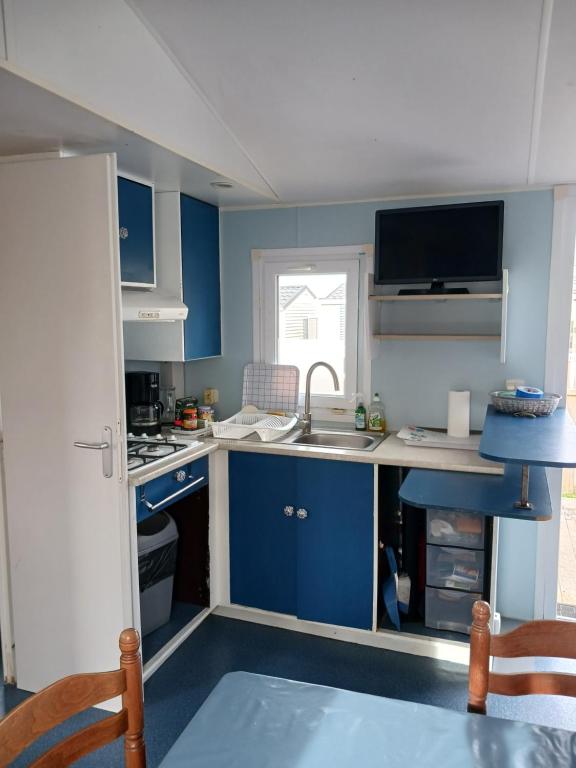 a small kitchen with blue cabinets and a sink at Mobil home L42 in Le Portel