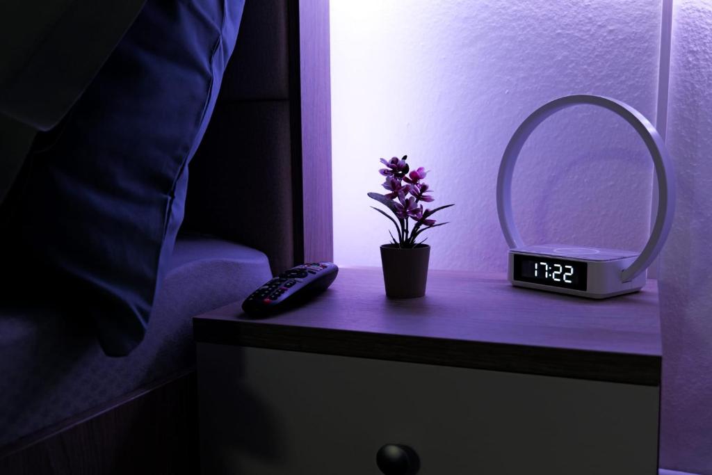 une horloge et une fleur sur une table de chevet avec un miroir dans l'établissement Transylvanian Hideaway Apartment, à Sibiu