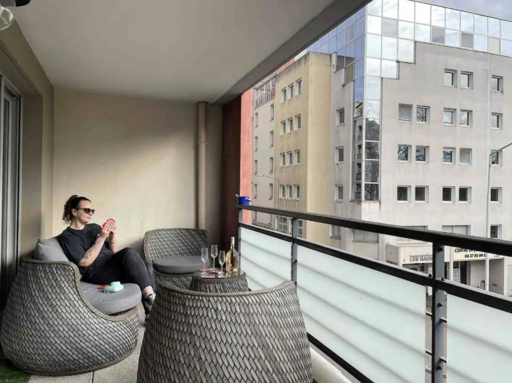 une femme assise sur une chaise sur un balcon dans l'établissement Centre des congrès / Confort, à Caluire-et-Cuire
