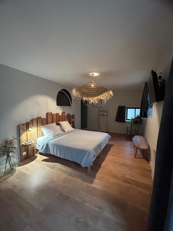 a bedroom with a large bed and a chandelier at Chambres d'hôtes de la pilatière in Persac