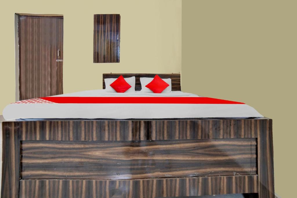 OYO Flagship Prakash Inn في جمشيدبور: سرير مع وسائد حمراء فوق منصة خشبية
