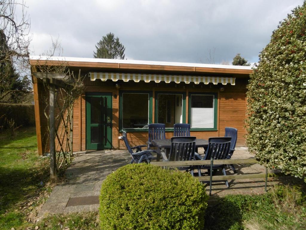 a house with chairs and a table on a patio at Ferienbungalow Am Birkenwäldchen in Kolonie Röntgental