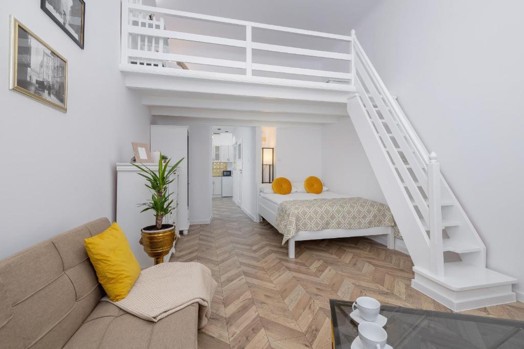 a living room with a bed and a staircase at Studio Apartment with Mezzanine near Kraków City Centre by Renters in Krakow