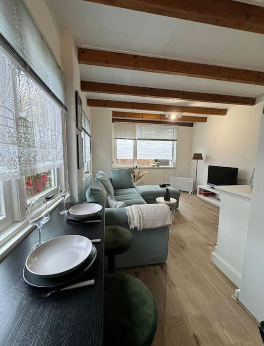 ein Wohnzimmer mit einem Sofa und einem Tisch in der Unterkunft Hello Noordwijk - Tiny House Dahliastraat 60 in Noordwijk