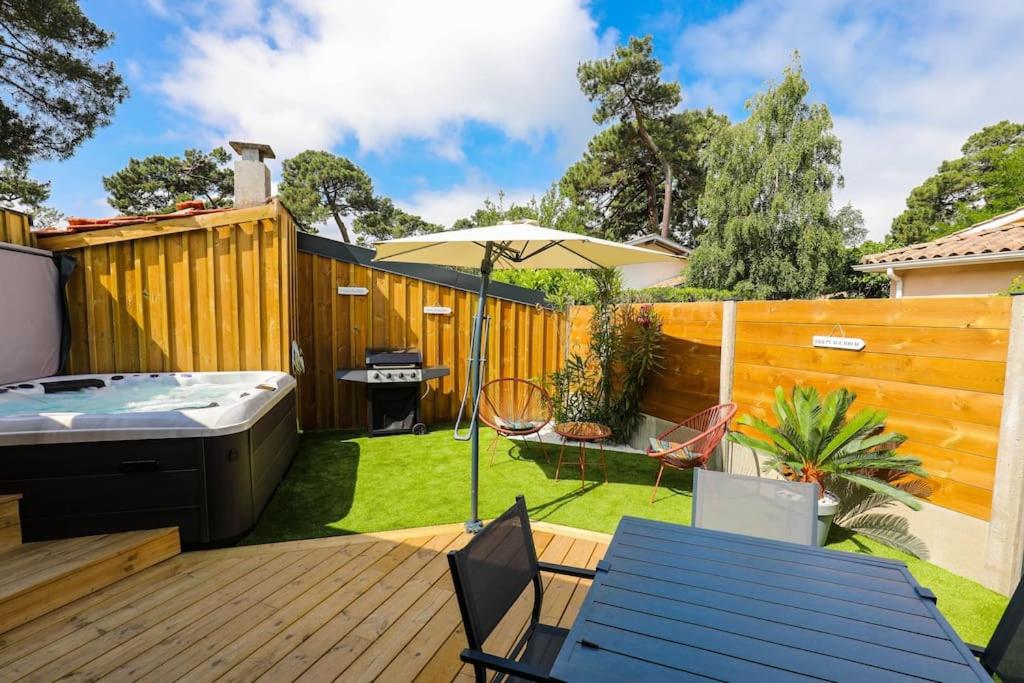 une arrière-cour avec un bain à remous et une terrasse en bois dans l'établissement Appartement plage à pied, à La Teste-de-Buch