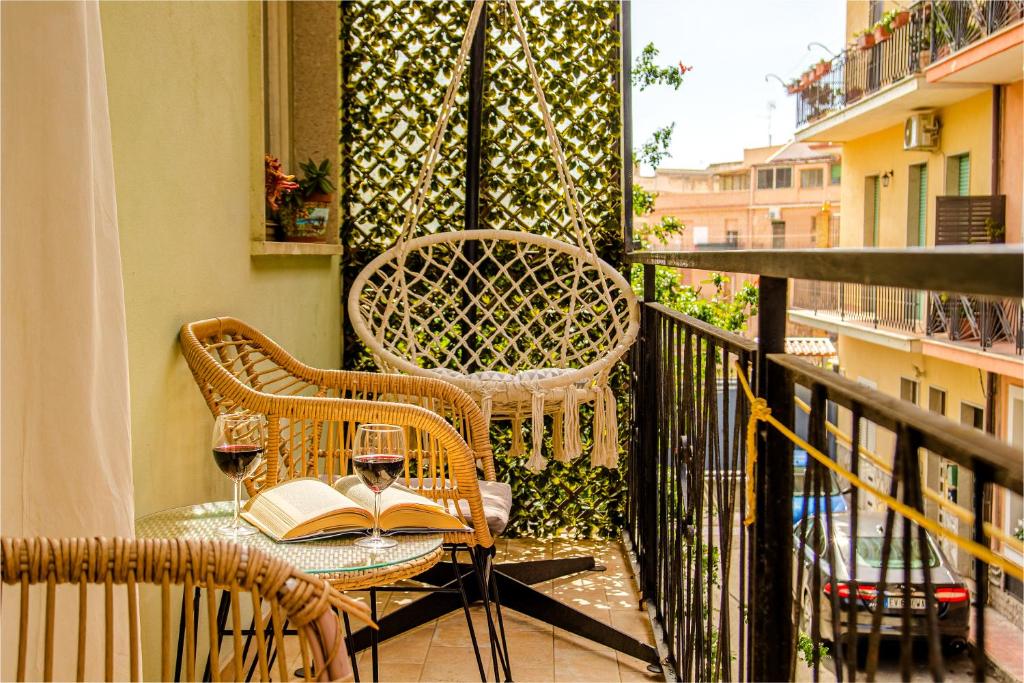 a table with a book and wine glasses on a balcony at Casa Inzolia in Giardini Naxos