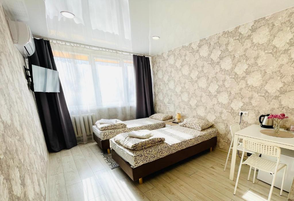 una camera con due letti, un tavolo e una finestra di Savan House "Easy Kaunas" a Kaunas