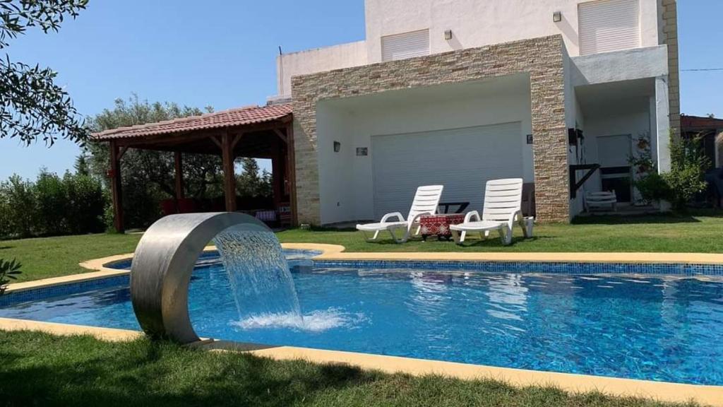 a swimming pool with a fountain in front of a house at Villa de luxe avec piscine in Korba
