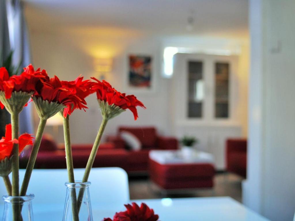 dos jarrones con flores rojas sentados en una mesa en Vakantiehuis Voor Anker, en Egmond aan Zee