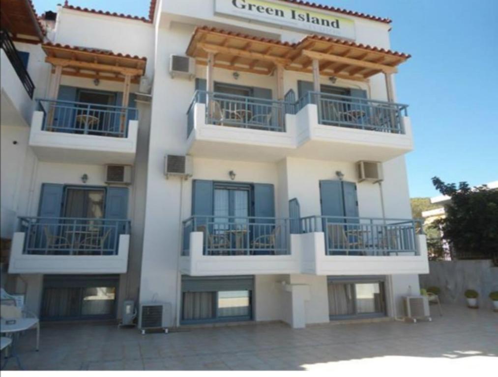 a white building with balconies and a sign on it at Green Island Studios in Skala