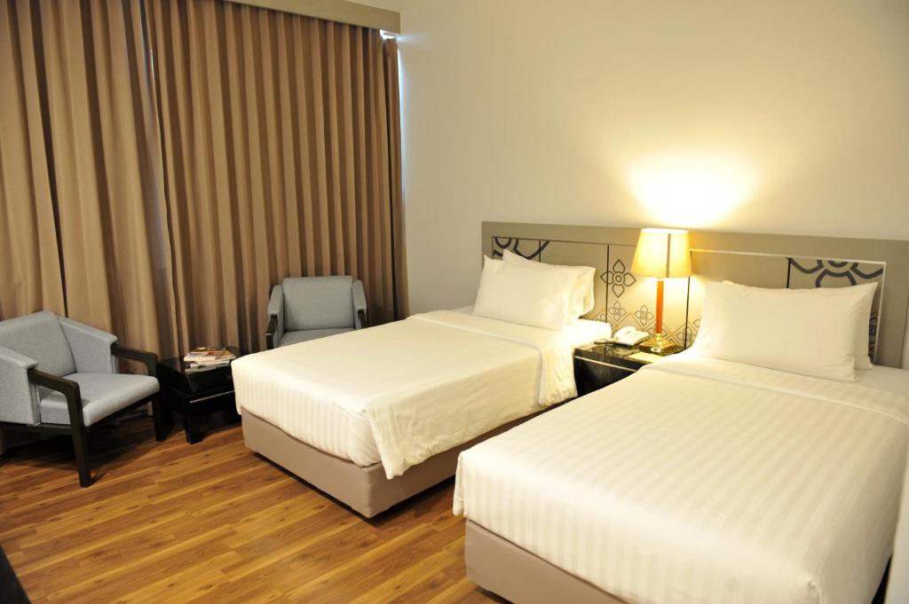 a hotel room with two beds and a chair at New Season Hotel in Hat Yai