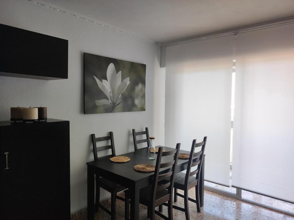 a dining room with a black table and chairs at Alojamiento El palmeral in Santa Pola