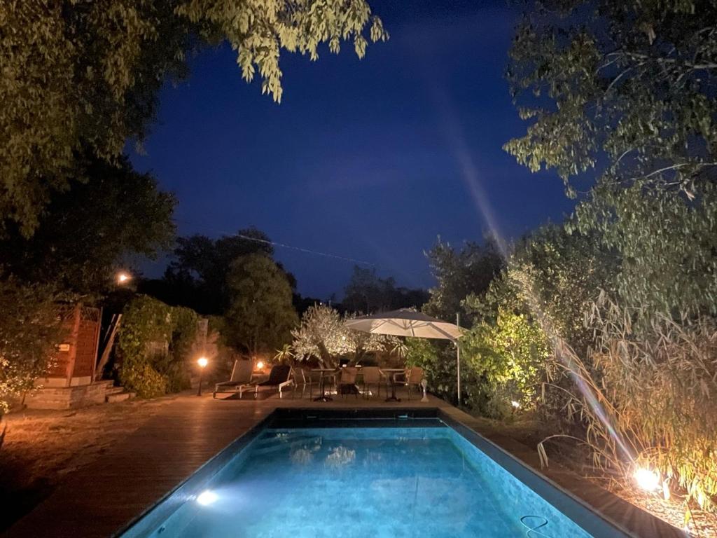 uma piscina num quintal à noite em L Amourier chambres d hôtes pour amoureux avec Jacuzzi ou baignoire XXL em Saint-Hippolyte-du-Fort