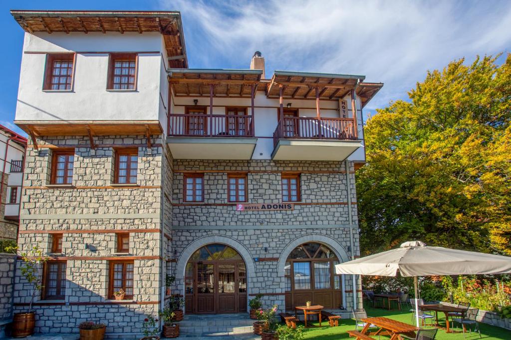 un bâtiment avec un parasol devant lui dans l'établissement Hotel Adonis, à Metsovo