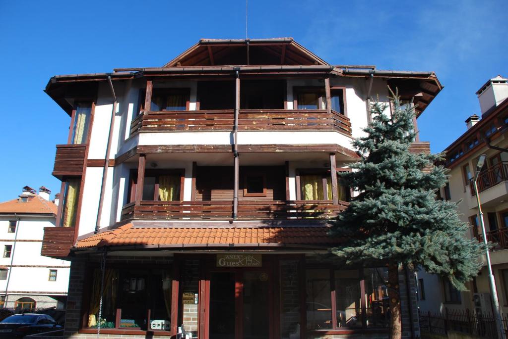 a tall building with wooden balconies and a tree at Guest House ANEX in Bansko