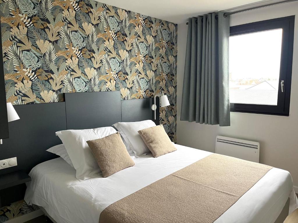 - une chambre avec un grand lit et du papier peint floral dans l'établissement Logis - Hôtel de la Baie de Somme, au Crotoy