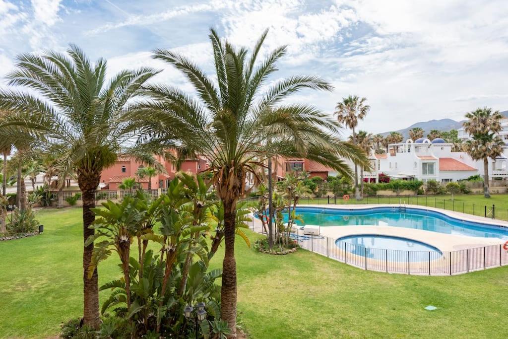 un resort con piscina e palme di Playa de Los Álamos-Playamar Torremolinos Málaga. a Torremolinos