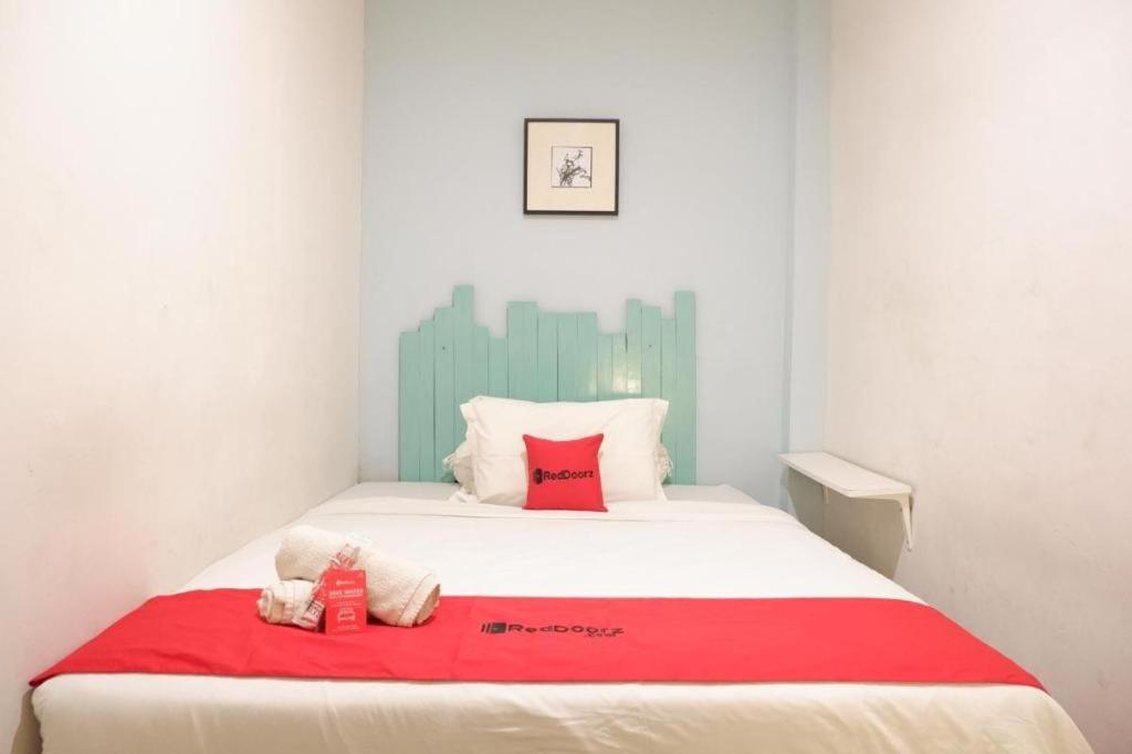 a bedroom with a bed with a red blanket at RedDoorz @ Just in Mataram City in Mataram