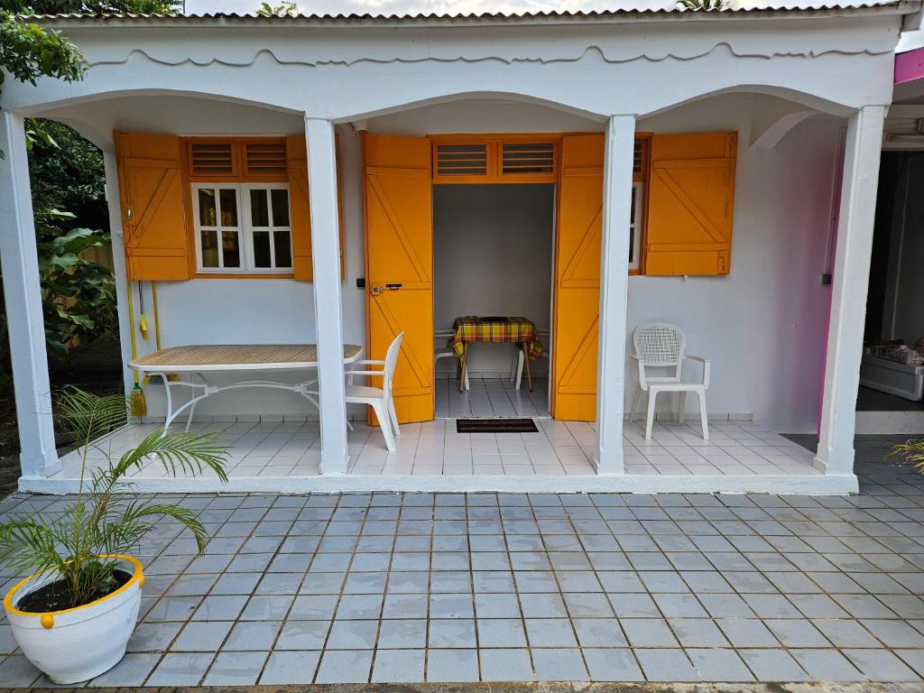 a small house with orange doors and a table at Au Paradis Créole in Dubédou