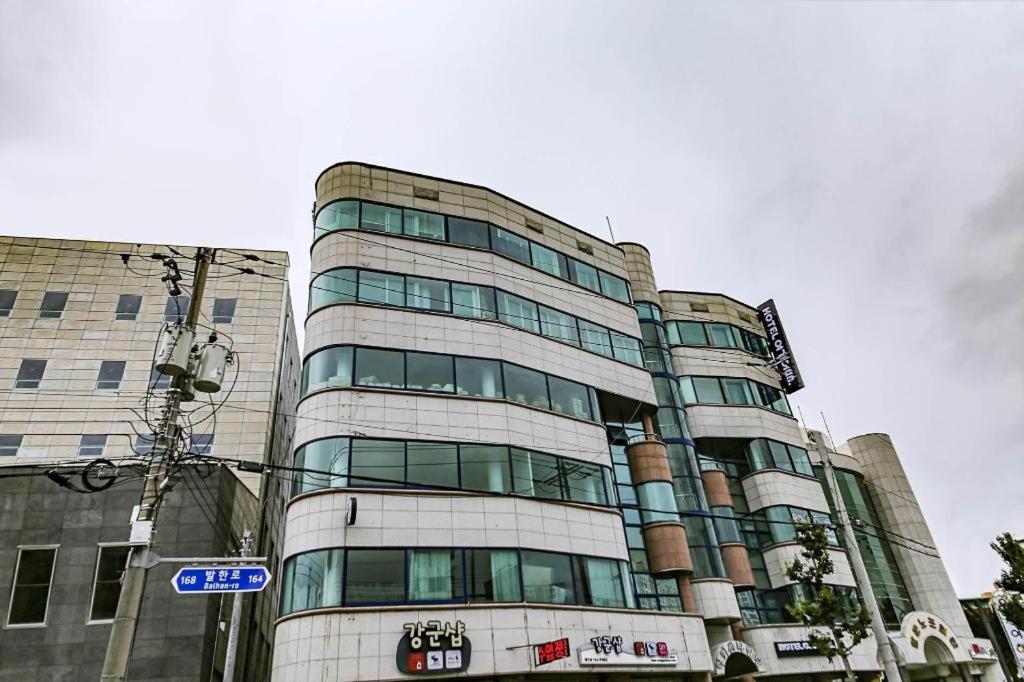 a tall building with glass windows and a street sign at Hotel Yeogiuhtte Donghae Mukho in Donghae
