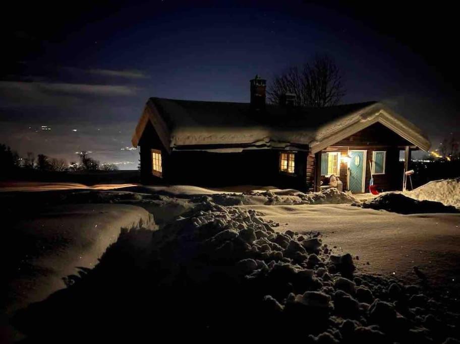 a house covered in snow at night with lights on at Koselig hytte 10 minutter fra Lillehammer sentrum in Lillehammer