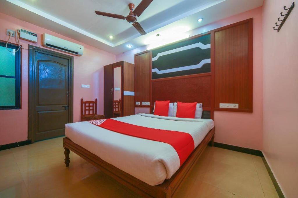 a bedroom with a large bed with red pillows at OYO Gnana S.R.M Residency in Puducherry