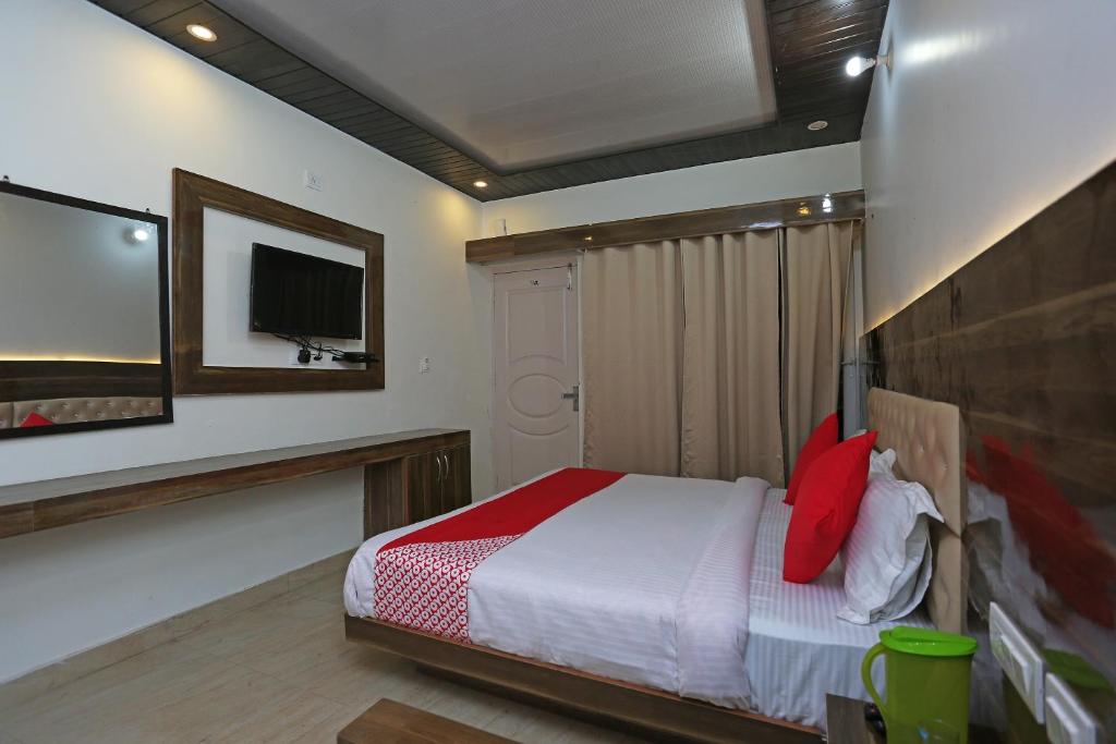 - une chambre avec un lit et une télévision murale dans l'établissement OYO The Mountain Dream, à Mussoorie
