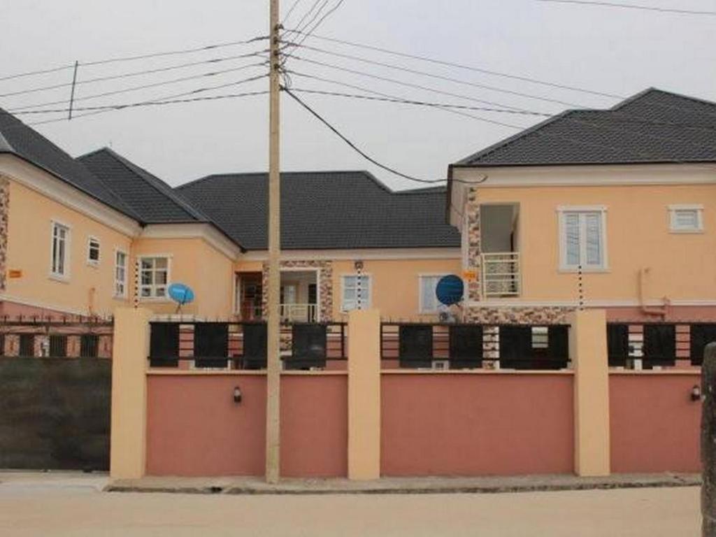 duży dom z płotem przed nim w obiekcie Ayoluyem Aparthotel and Suites w mieście Ogbodo