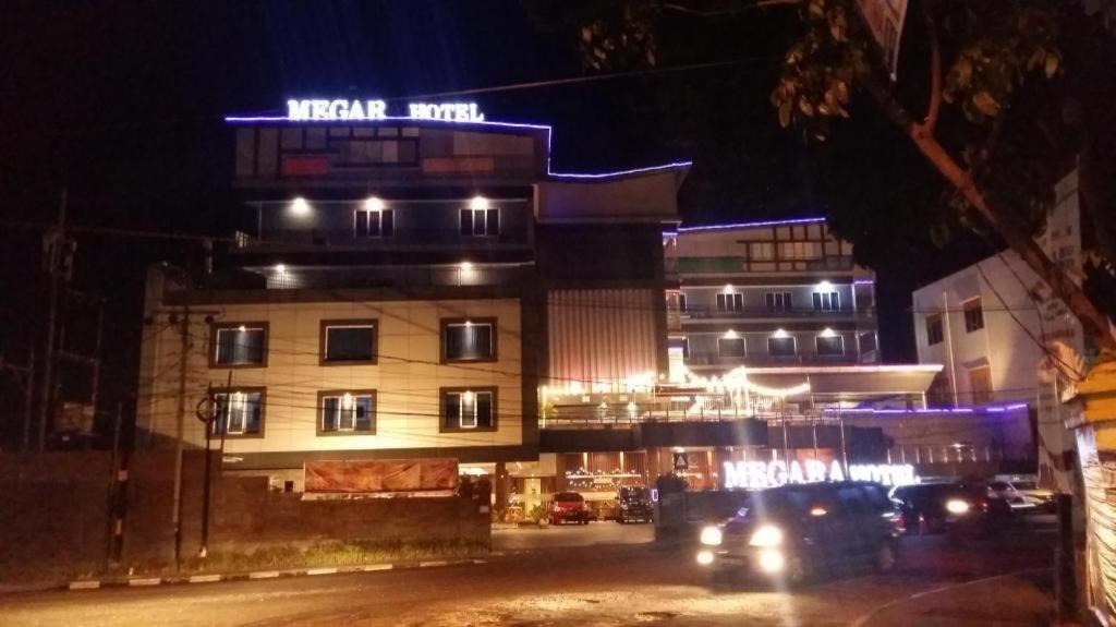 un edificio de noche con coches aparcados delante de él en MEGARA HOTEL PEKANBARU, en Pekanbaru