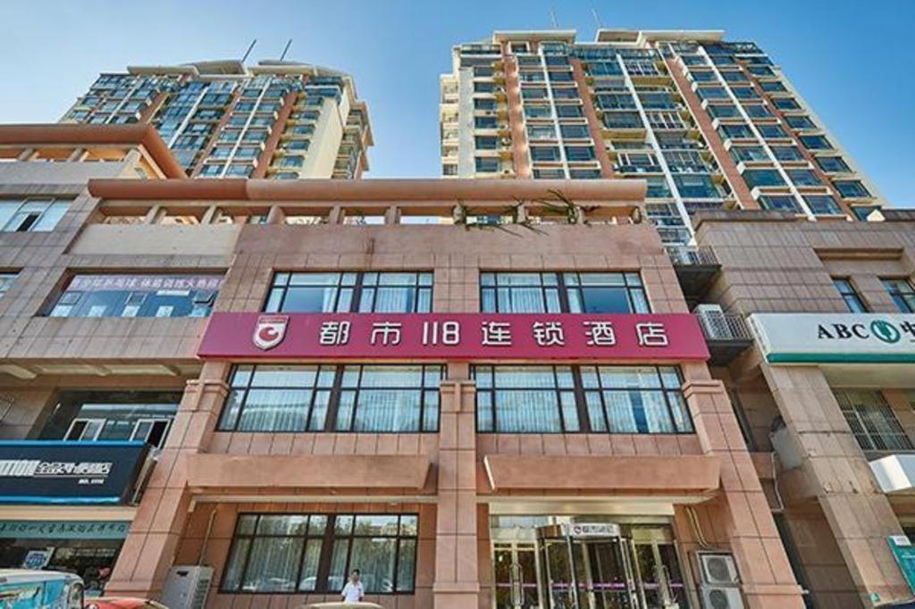 budynek z dwoma wysokimi budynkami w tle w obiekcie City 118 Hotel Qingdao Boardcast Tower w mieście Qingdao
