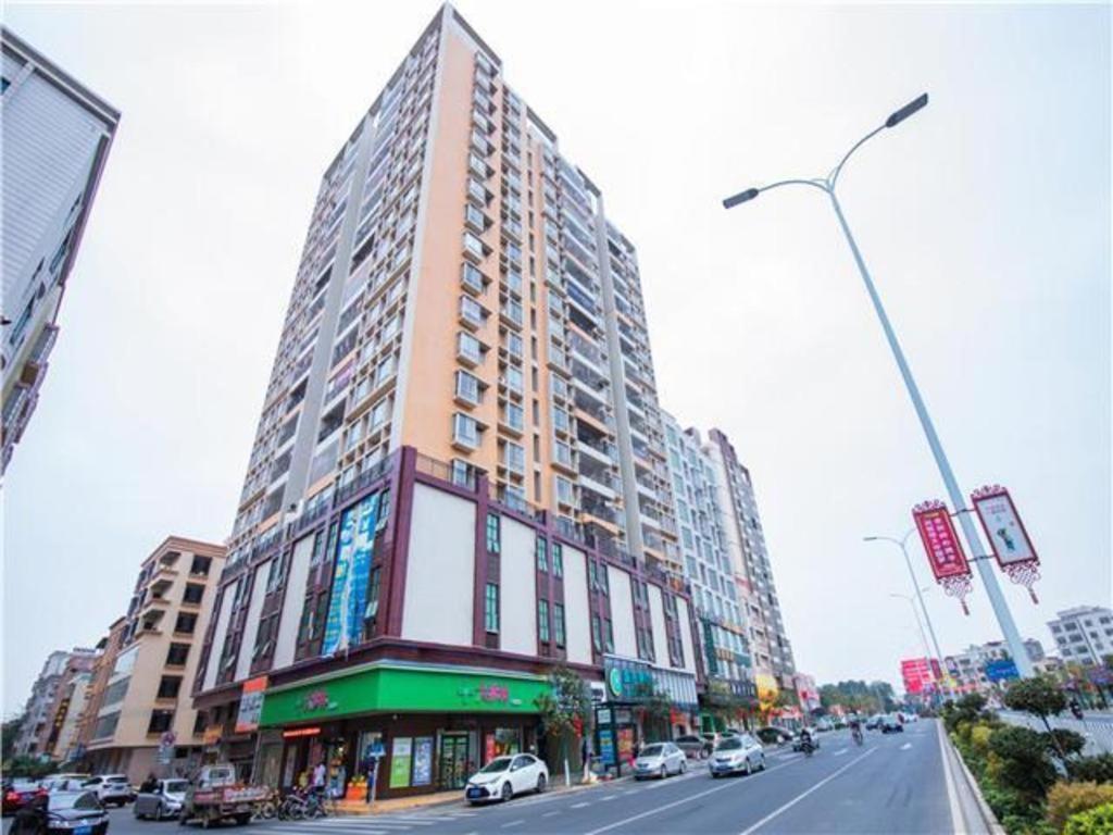 un gran edificio alto en una calle de la ciudad con coches en City Comfort Inn Hotel Maoming Huazhou Wanda Plaza, en Dongshan