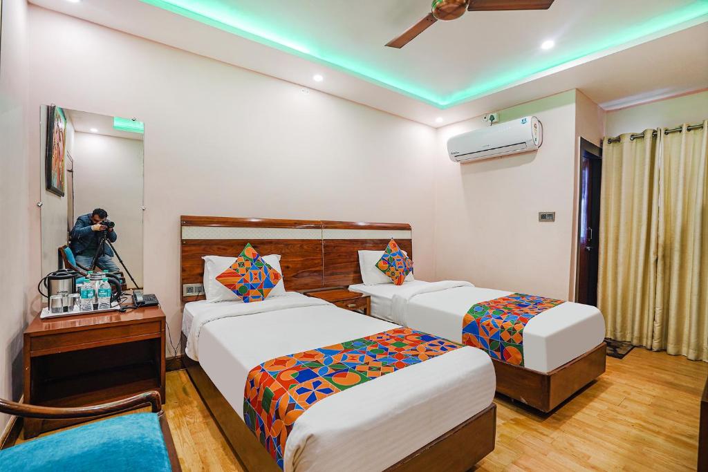 un hombre tomando una foto de una habitación de hotel con dos camas en FabHotel Prime Stay inn I, en Varanasi