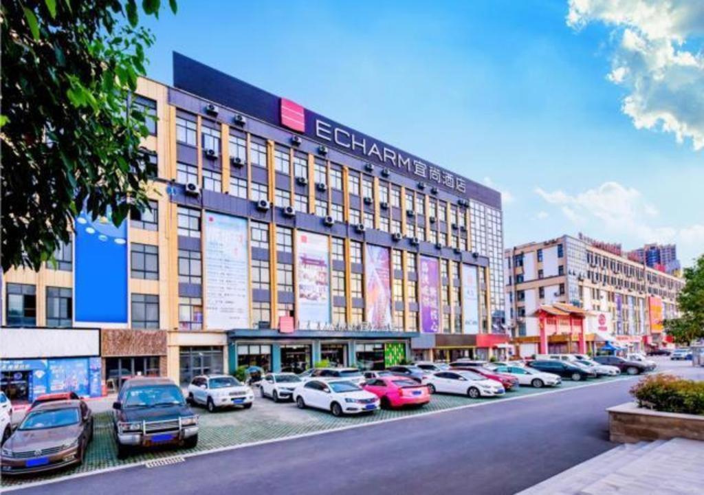duży budynek z samochodami zaparkowanymi na parkingu w obiekcie Echarm Hotel Qianxi High Speed Railway Station w mieście Qianxi