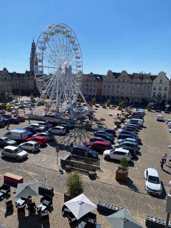 une grande roue ferris dans un parking avec des voitures dans l'établissement The Best View 46 Grand place Superbe vue Beffroi, à Arras