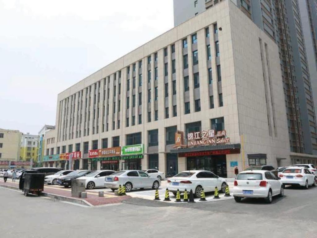a large building with cars parked in a parking lot at Jinjiang Inn Select Heze Wanxiang Plaza Guiling Road in Heze