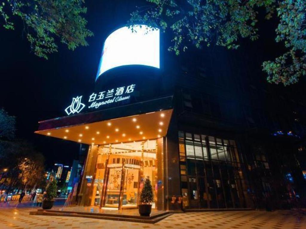 budynek z znakiem na górze w nocy w obiekcie Magnotel Hotel Guangyuan Nanhe Bus Station Beijing Road w Guangyuan