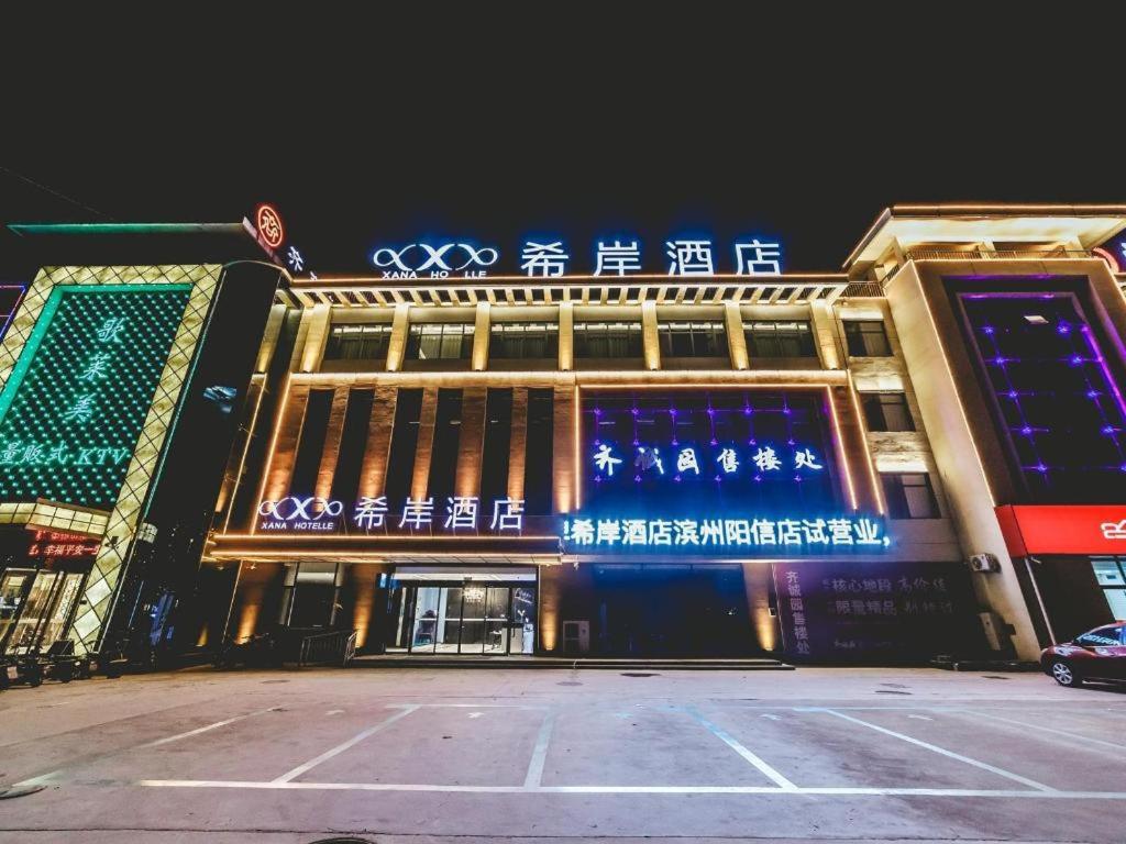 a building with a sign on the front of it at Xana Hotelle Binzhou Yangxin in Binzhou
