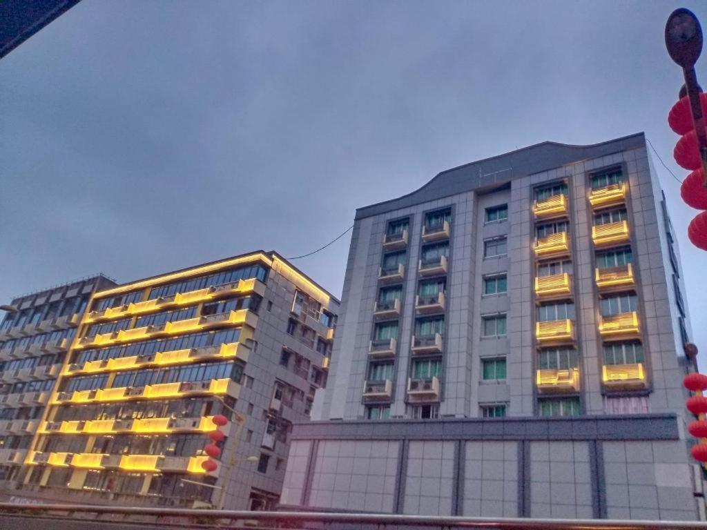 zwei hohe Gebäude mit eingeschaltetem Licht in einer Stadt in der Unterkunft PAI Hotel Nanchong Huaxi Normal University in Nanchong