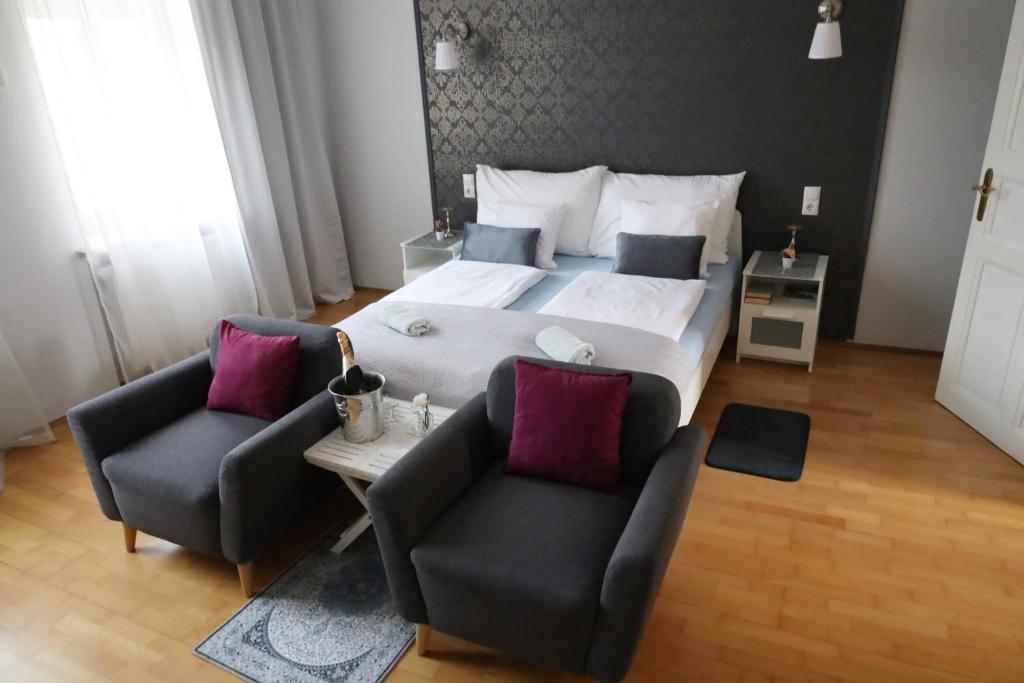 a bedroom with a large bed and two chairs at Arena Apartments in Graz