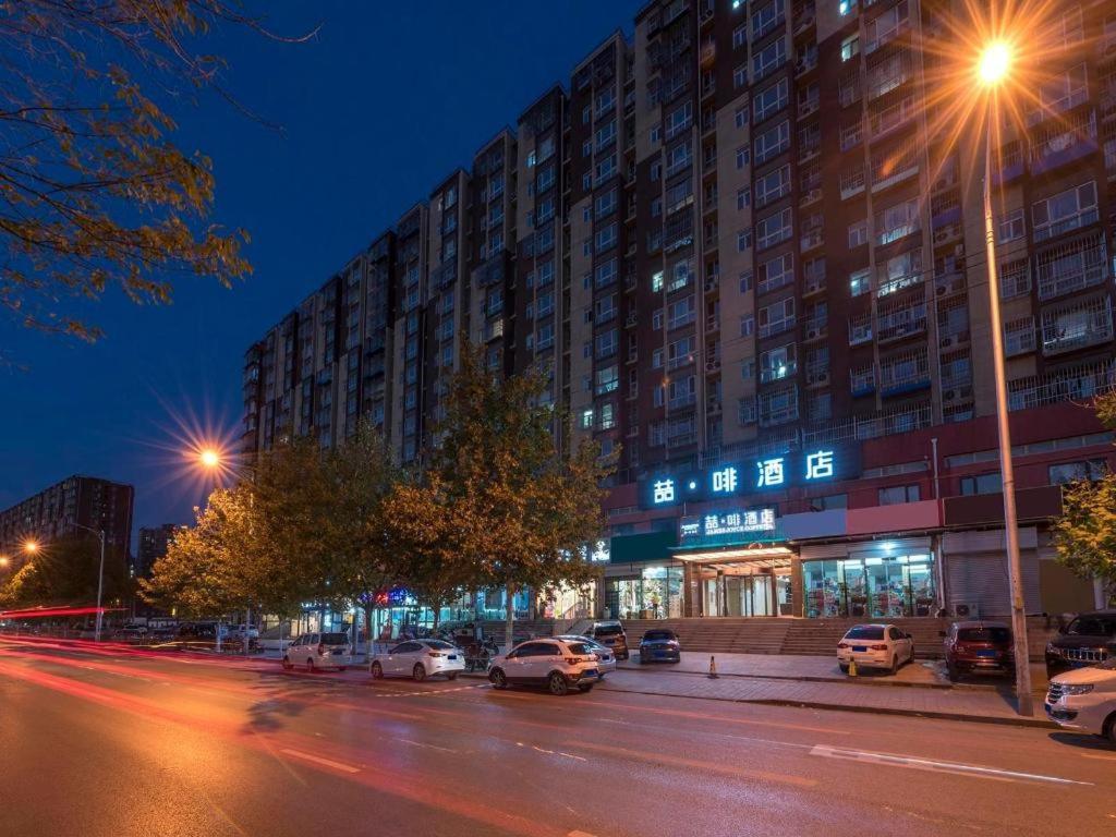 eine Stadtstraße mit Autos, die vor einem Gebäude geparkt sind in der Unterkunft James Joyce Coffetel Beijing South Station Xingong Metro Station Dayue Chunfengli in Peking